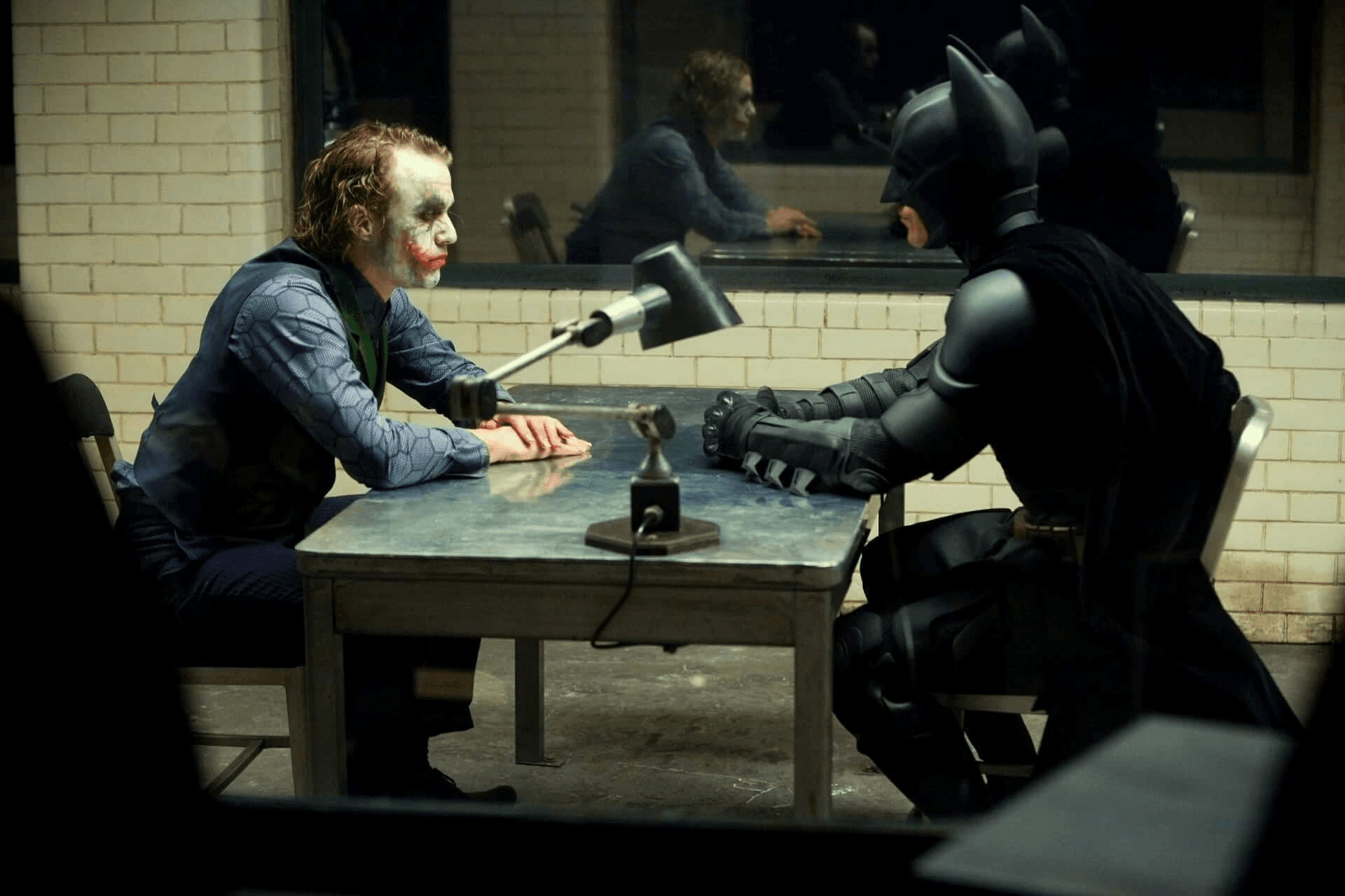 Joker and Batman sitting in an interrogation room