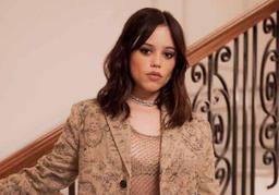 Jenna Ortega standing against a stairwell in a photoshoot