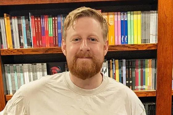 Michael Patrick standing against a bookshelf 