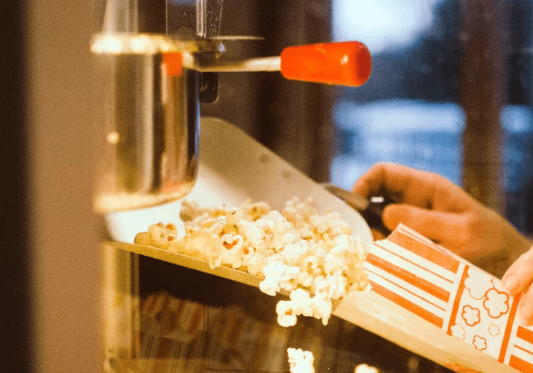 A person filling a popcorn bucket