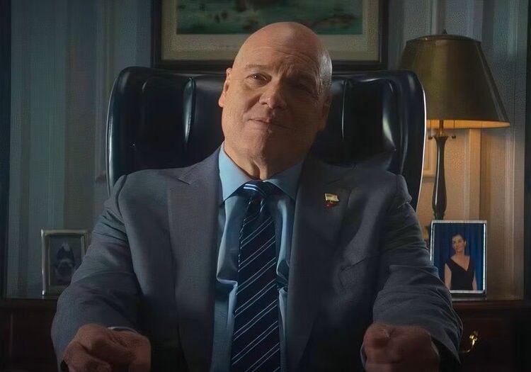 Wilson Fisk sitting at his mayor's office desk in a grey suit