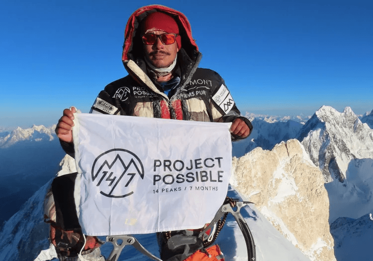Nims Dai holding a flag on a summit